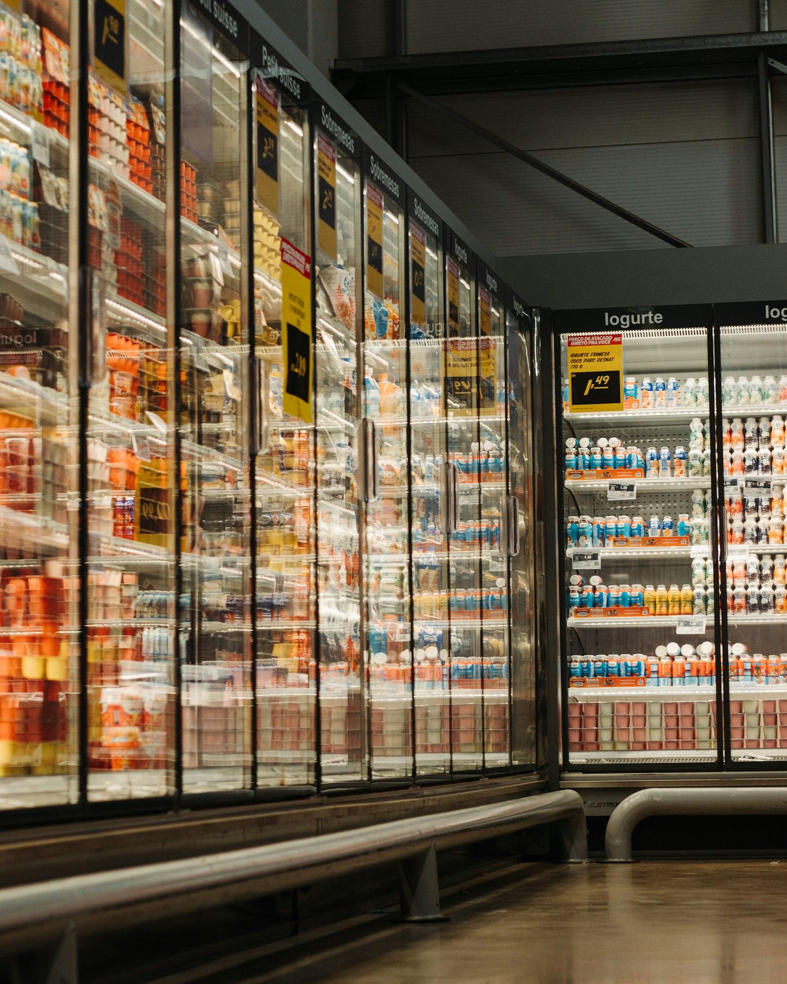 Row of glass-door chiller cabinets stocked with dairy products and drinks